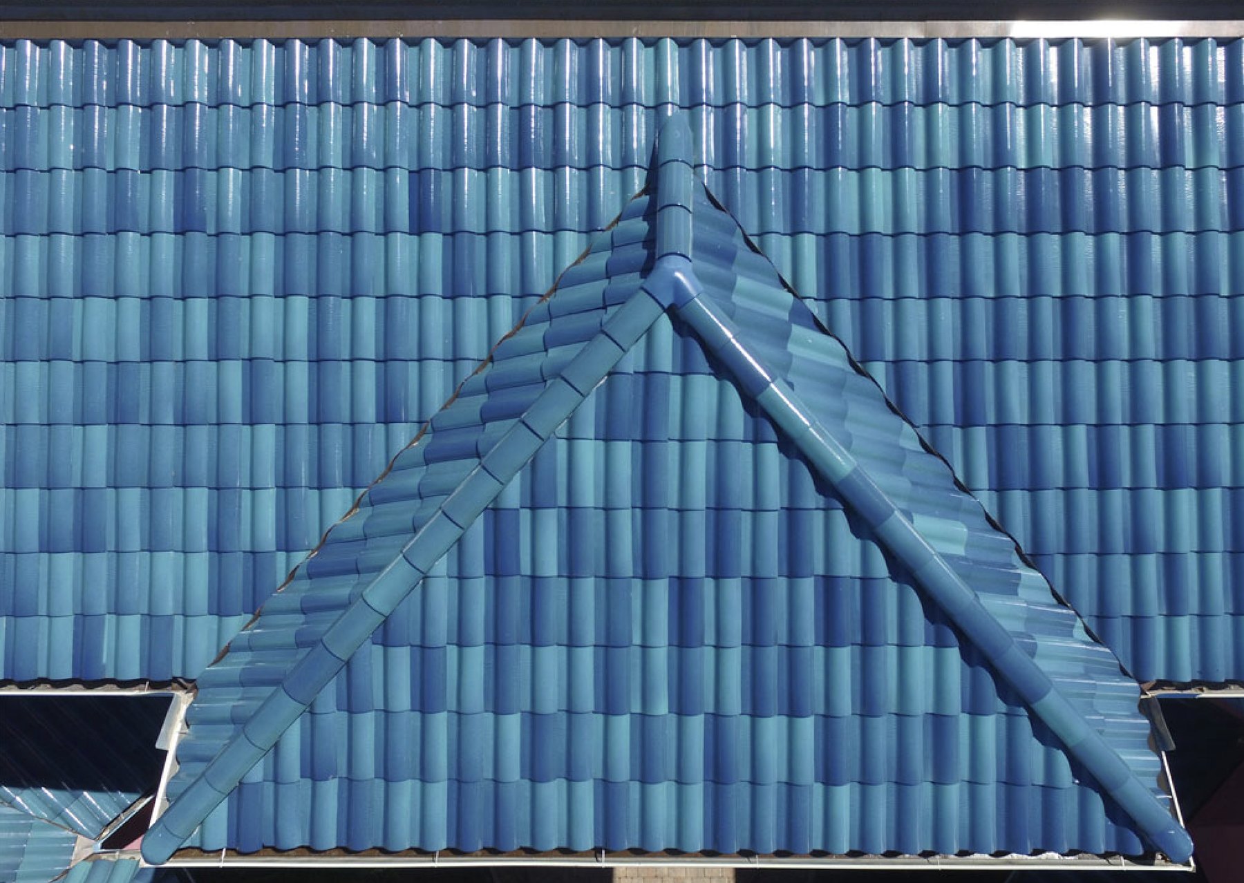Close-up of glazed blue clay barrel tile hips and ridge on a Carrollwood home